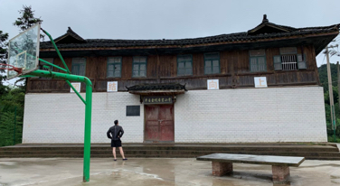 Person standing in front of a traditional wooden building with a basketball hoop