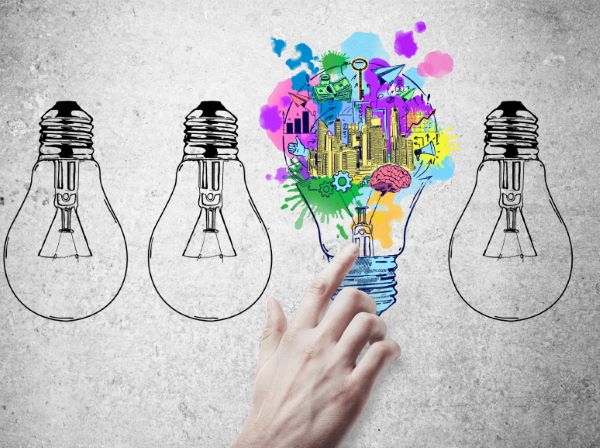 Hand pointing at colorful, creative light bulb